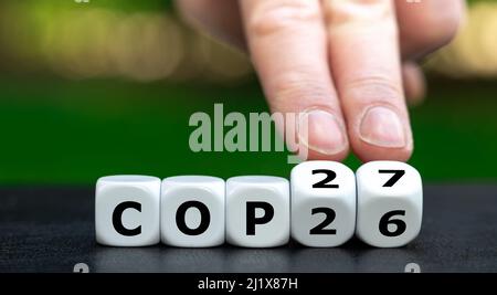 Symbol für die nächste Klimakonferenz COP27. Hand dreht Würfel und ändert den Ausdruck COP26 in COP27. Stockfoto
