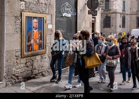 Barcelona, Spanien. 28. März 2022. Die Menschen blicken hinter den Gittern an einem Porträt von Wladimir Putin vorbei. Vladimir Putin Behind Bars ist in der neuen öffentlichen grafischen Collage auf der Plaza de Sant Jaume des in Barcelona lebenden italienischen Künstlers TvBoy vertreten. (Foto von Paco Freire/SOPA Images/Sipa USA) Quelle: SIPA USA/Alamy Live News Stockfoto