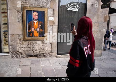 Barcelona, Spanien. 28. März 2022. Eine Frau fotografiert das Porträt von Wladimir Putin hinter den Gittern. Vladimir Putin Behind Bars ist in der neuen öffentlichen grafischen Collage auf der Plaza de Sant Jaume des in Barcelona lebenden italienischen Künstlers TvBoy vertreten. (Foto von Paco Freire/SOPA Images/Sipa USA) Quelle: SIPA USA/Alamy Live News Stockfoto