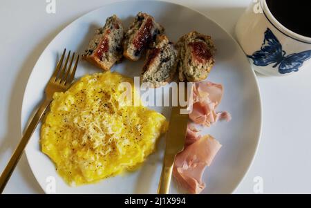 Rührei mit Schinken, einem Blaubeer-Muffin und schwarzem Kaffee Stockfoto