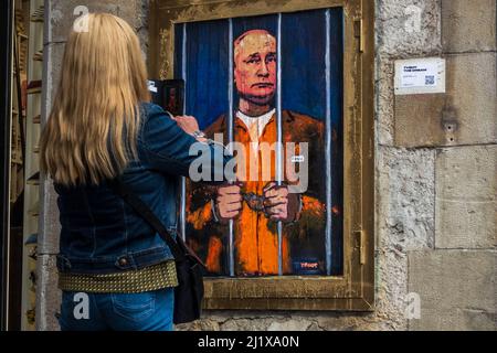 Barcelona, Spanien. 28. März 2022. Ein Pendler fotografiert ein Graffiti des italienischen Stadtkünstlers „TVBoy“, Salvatore Benintende, mit dem Titel „der Traum“, auf dem der russische Präsident Wladimir Putin aus Protest gegen die anhaltenden russischen Angriffe im Gefängnis und hinter Gittern abgebildet ist.Quelle: Matthias Oesterle/Alamy Live News Stockfoto