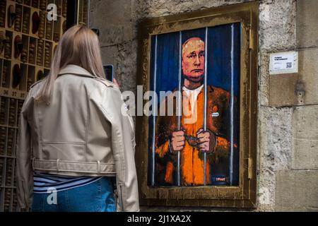 Barcelona, Spanien. 28. März 2022. Ein Pendler fotografiert ein Graffiti des italienischen Stadtkünstlers „TVBoy“, Salvatore Benintende, mit dem Titel „der Traum“, auf dem der russische Präsident Wladimir Putin aus Protest gegen die anhaltenden russischen Angriffe im Gefängnis und hinter Gittern abgebildet ist.Quelle: Matthias Oesterle/Alamy Live News Stockfoto