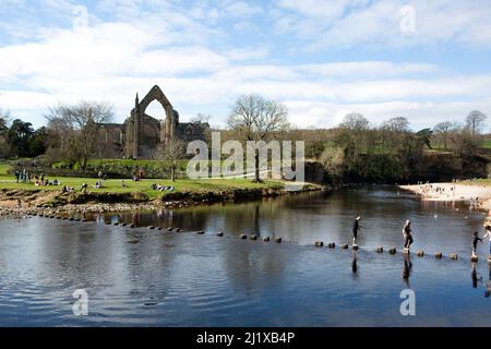 Menschen versuchen, die Trittsteine über den Fluss Wharfe in Bolton Abbey in North Yorkshire zu überqueren. Stockfoto