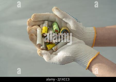 Nahaufnahme der weiblichen Hände in Baumwollschutzhandschuhen mit gebrauchten Alkali-Batterien Stockfoto