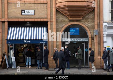 Vor einer Sandwich-Bar in London stehen die Leute zur Mittagszeit Schlange, da in England in der Vorwoche die Anweisungen von der Arbeit von zu Hause entfernt wurden. Stockfoto