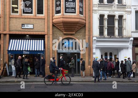 Vor einer Sandwich-Bar in London stehen die Leute zur Mittagszeit Schlange, da in England in der Vorwoche die Anweisungen von der Arbeit von zu Hause entfernt wurden. Stockfoto