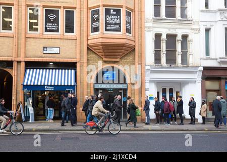 Vor einer Sandwich-Bar in London stehen die Leute zur Mittagszeit Schlange, da in England in der Vorwoche die Anweisungen von der Arbeit von zu Hause entfernt wurden. Stockfoto