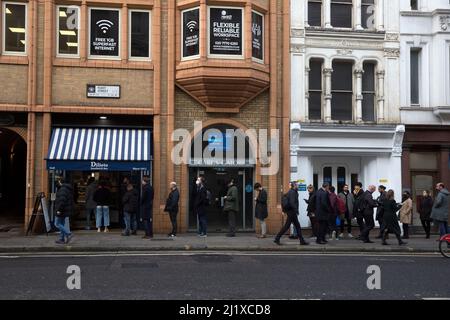 Vor einer Sandwich-Bar in London stehen die Leute zur Mittagszeit Schlange, da in England in der Vorwoche die Anweisungen von der Arbeit von zu Hause entfernt wurden. Stockfoto