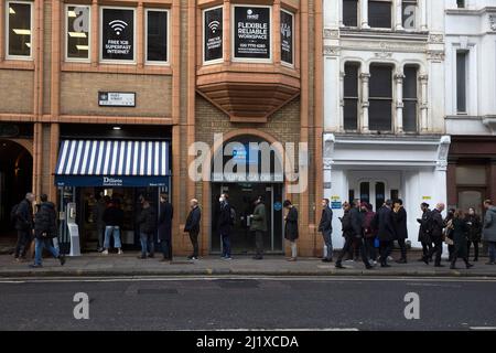 Vor einer Sandwich-Bar in London stehen die Leute zur Mittagszeit Schlange, da in England in der Vorwoche die Anweisungen von der Arbeit von zu Hause entfernt wurden. Stockfoto