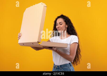 Young Lady Holding Box Beim Blick Auf Pizza Im Studio Stockfoto
