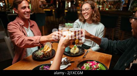 Eine Gruppe verschiedener Freunde, die zum Abendessen zum Toasten gehen Stockfoto