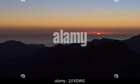 Panoramablick über die zerklüfteten Berge der Insel Gran Canaria, Kanarische Inseln, Spanien bei Sonnenuntergang mit buntem Himmel und Sonnenuntergang am Horizont. Stockfoto