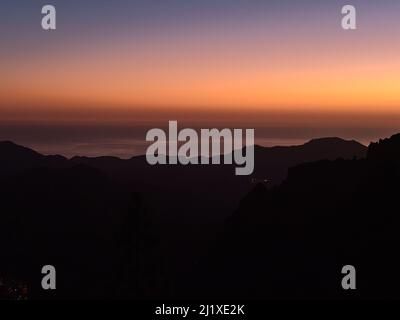 Schöner Blick über die südlichen Berge der Insel Gran Canaria, Kanarische Inseln, Spanien nach Sonnenuntergang mit buntem Himmel über dem Atlantischen Ozean. Stockfoto