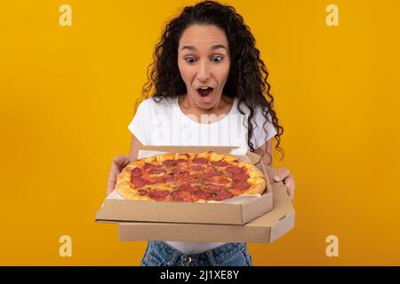Schockierte Frau, Die Box Mit Pizza Im Studio Hält Stockfoto