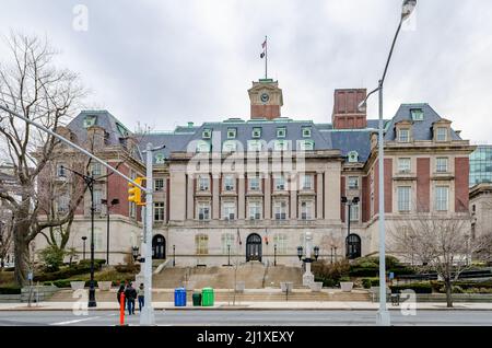 Staten Island Borough Hall mit Ampeln und Menschen, die die Straße im Vordergrund überqueren, New York City, während des Wintertages mit bewölktem, horizontales Licht Stockfoto