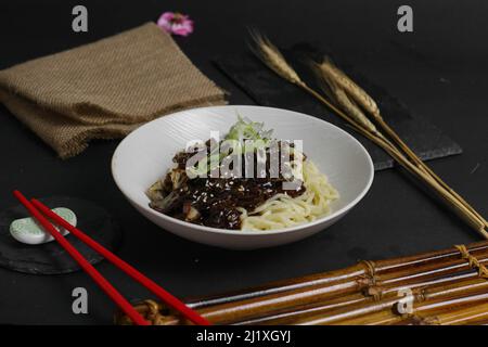 Eine Nahaufnahme eines Tellers voll Jajangmyeon, serviert mit Stöcken in einem Restaurant Stockfoto