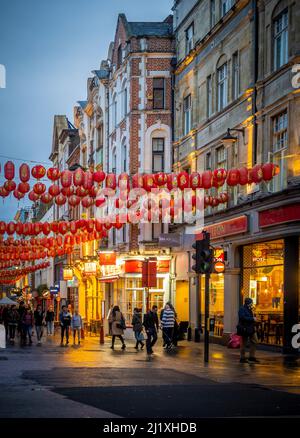 Rote Papierlaternen hängen in der Wardour Street, einem Teil des Stadtviertels von China, in der Abenddämmerung über der Straße. London. Stockfoto