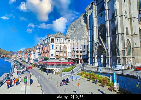 Dinant, Belgien - März 9. 2022: Blick über die gotische Kirche, Felswand auf der Uferpromenade des Flusses meuse mit Cafés und Restaurants Stockfoto