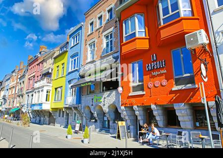 Dinant, Belgien - März 9. 2022: Blick auf die Straße mit typischen bunten Häusern gegen blauen Himmel, flauschige Wolken Stockfoto