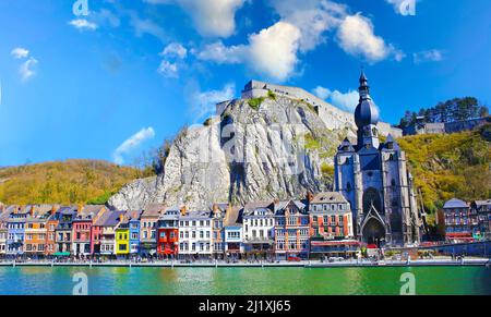 Dinant, Belgien - März 9. 2022: Blick über den Fluss maas auf eine malerische Reihe von alten bunten Häusern, Felswand mit Zitadelle, gotische Kirche gegen cle Stockfoto