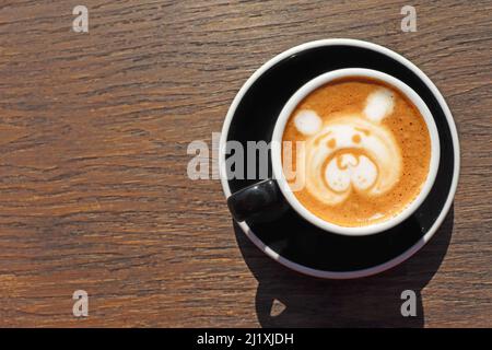 Latte Art, Zeichnung des Gesichts des Bären, Kaffeekunst von Barista auf Holzhintergrundtisch, Blick von oben oder von oben. Platz für Text auf der linken Seite kopieren Stockfoto