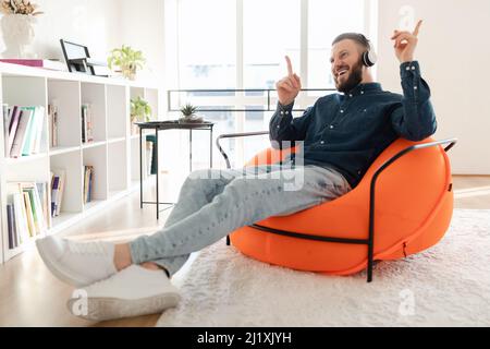 Mann Mit Kopfhörern Musik Hören In Innenräumen, Seitenansicht Stockfoto