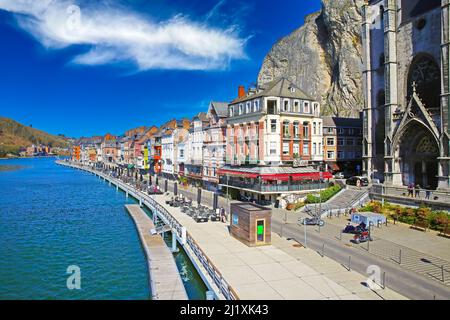 Dinant, Belgien - März 9. 2022: Blick über die gotische Kirche, Felswand auf der Uferpromenade des Flusses meuse mit Cafés und Restaurants Stockfoto