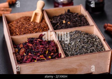 Verschiedene Arten von trockenem Tee - grün, schwarz, Minze, Rose und Kamille, Holzlöffel in der Box Stockfoto