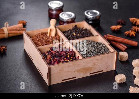 Verschiedene Arten von trockenem Tee - grün, schwarz, Minze, Rose und Kamille, Holzlöffel in der Box Stockfoto