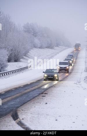 Der Verkehr auf der A417 außerhalb von Cirencester kämpft mit nächtlichem Schnee, Spray und Eis, was gefährliche Fahrbedingungen zur Verfügung stellt. Stockfoto