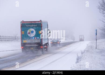 Der Verkehr auf der A417 außerhalb von Cirencester kämpft mit nächtlichem Schnee, Spray und Eis, was gefährliche Fahrbedingungen zur Verfügung stellt. Stockfoto