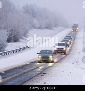 Der Verkehr auf der A417 außerhalb von Cirencester kämpft mit nächtlichem Schnee, Spray und Eis, was gefährliche Fahrbedingungen zur Verfügung stellt. Stockfoto