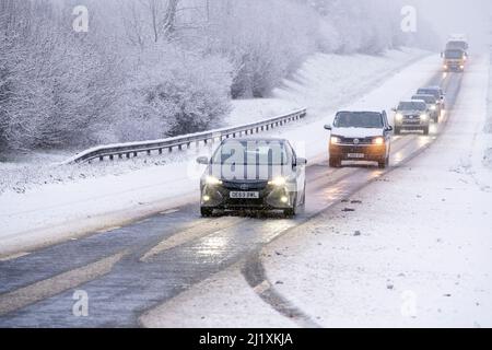 Der Verkehr auf der A417 außerhalb von Cirencester kämpft mit nächtlichem Schnee, Spray und Eis, was gefährliche Fahrbedingungen zur Verfügung stellt. Stockfoto