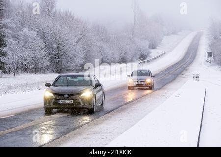 Der Verkehr auf der A417 außerhalb von Cirencester kämpft mit nächtlichem Schnee, Spray und Eis, was gefährliche Fahrbedingungen zur Verfügung stellt. Stockfoto