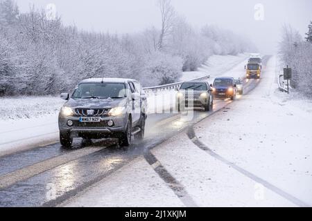 Der Verkehr auf der A417 außerhalb von Cirencester kämpft mit nächtlichem Schnee, Spray und Eis, was gefährliche Fahrbedingungen zur Verfügung stellt. Stockfoto