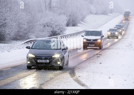 Der Verkehr auf der A417 außerhalb von Cirencester kämpft mit nächtlichem Schnee, Spray und Eis, was gefährliche Fahrbedingungen zur Verfügung stellt. Stockfoto