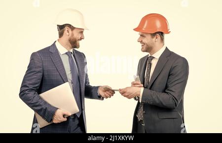 Investition in Architekturprojekt. Männer Geschäftsleute in Hardhat mit Geld und Laptop. Stockfoto