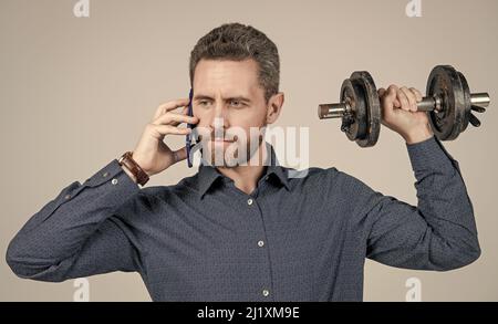 Kommunikation. Gutaussehender Geschäftsmann mit Hantel sprechen am Telefon. Digitaler Sport. Stockfoto