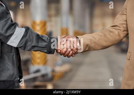 Nahaufnahme eines Managers, der dem Arbeiter die Hände schüttelt, um ihn für einen Job in der Fabrik zu bewerben Stockfoto