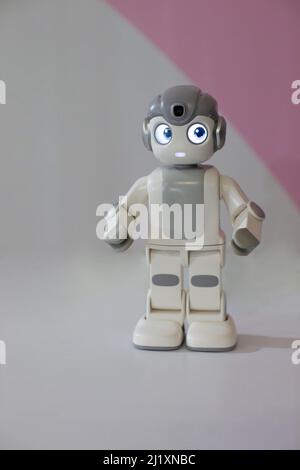 Figur eines kleinen Roboters auf grauem Hintergrund. Stockfoto