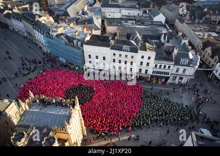 Cirencester, Großbritannien. Am Marktplatz der Stadt Cirencester versammeln sich Menschen, um einen Weltrekord zu bilden (anstehende Exformation), um an das Ende des Ersten Weltkriegs vor 100 Jahren zu erinnern. Über 3.300 Menschen trugen farbige Ponchos, um die Form eines Mohns und eines Blattes zu kreieren. Stockfoto