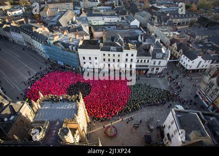 Cirencester, Großbritannien. Am Marktplatz der Stadt Cirencester versammeln sich Menschen, um einen Weltrekord zu bilden (anstehende Exformation), um an das Ende des Ersten Weltkriegs vor 100 Jahren zu erinnern. Über 3.300 Menschen trugen farbige Ponchos, um die Form eines Mohns und eines Blattes zu kreieren. Stockfoto