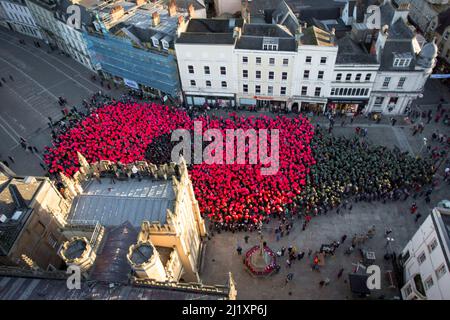 Cirencester, Großbritannien. Am Marktplatz der Stadt Cirencester versammeln sich Menschen, um einen Weltrekord zu bilden (anstehende Exformation), um an das Ende des Ersten Weltkriegs vor 100 Jahren zu erinnern. Über 3.300 Menschen trugen farbige Ponchos, um die Form eines Mohns und eines Blattes zu kreieren. Stockfoto