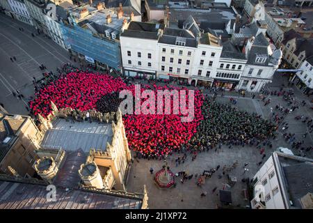 Cirencester, Großbritannien. Am Marktplatz der Stadt Cirencester versammeln sich Menschen, um einen Weltrekord zu bilden (anstehende Exformation), um an das Ende des Ersten Weltkriegs vor 100 Jahren zu erinnern. Über 3.300 Menschen trugen farbige Ponchos, um die Form eines Mohns und eines Blattes zu kreieren. Stockfoto