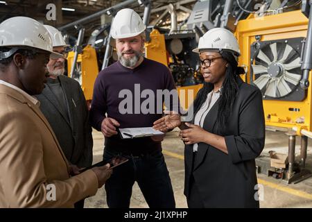 Business-Team diskutiert die Partnerschaft in der Bauindustrie stehen im Lager mit Maschinen im Hintergrund Stockfoto
