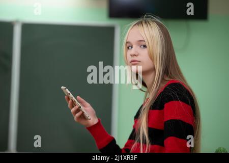 Teenager im höheren Schulalter. Ein Mädchen im Teenageralter steht vor einer Tafel. Stockfoto