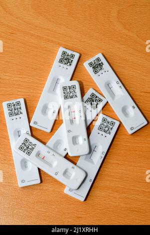 Positives Ergebnis bei einem lateralen Durchflusstest zusätzlich zu negativen Testergebnissen. Mit nicht identifizierbaren QR-Codes. Keine Personen. Stockfoto