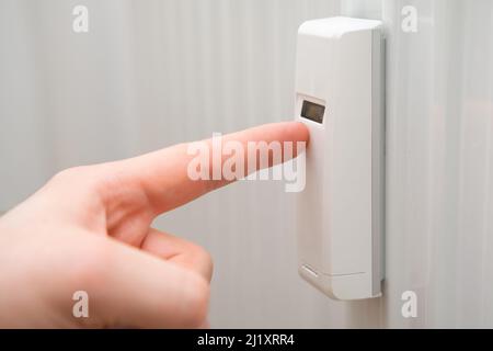 Nahaufnahme Mann zeigt auf dem Thermoregulator auf der Batterie. Steigende Kosten für Heizungs-, Gas- und Wasserkonzept. Stockfoto