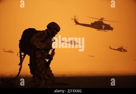 Militärtruppen und Hubschrauber auf dem Weg zum Schlachtfeld bei Sonnenuntergang. Stockfoto