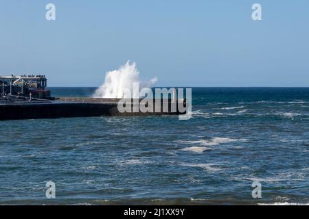 Wellen schlagen an einem sonnigen Tag gegen den Hafen von lekeitio in der kantabrischen See Stockfoto